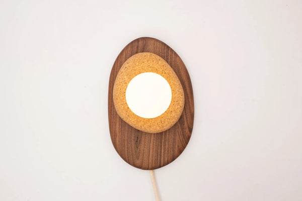 Pebble sconce in maple finish on white wall
