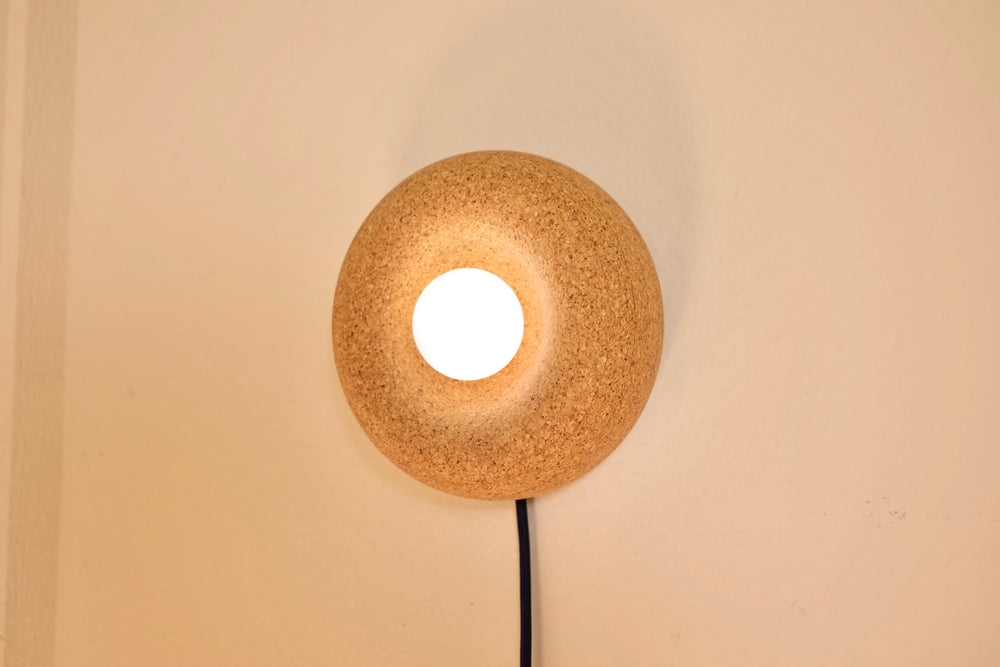 Cork wall sconce turned on showing warm dimmable light
