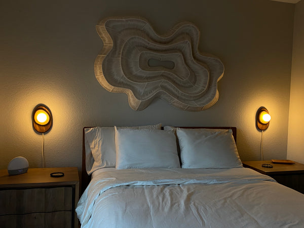 Pebble wall sconce installed above nightstand with fabric cord